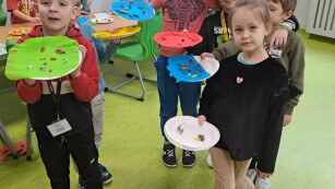 Grupa dzieci prezentuje prace plastyczną - Zdrowie na talerzu. Wyklejone z plasteliny produkty spożywcze.