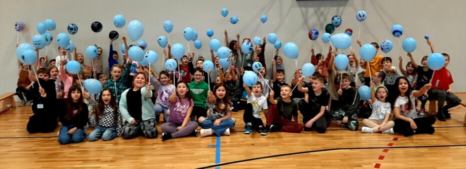 Grupa uczestników półkolonii z niebieskimi balonami.
