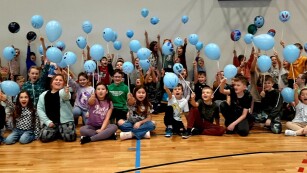 Grupa uczestników półkolonii z niebieskimi balonami.