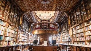 Wnętrze ogromnej biblioteki, na scianach drewniane półki wypełnione książkami.